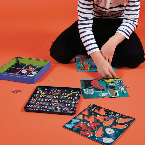 Magnetic fun and games tin open with child playing with games on orange background