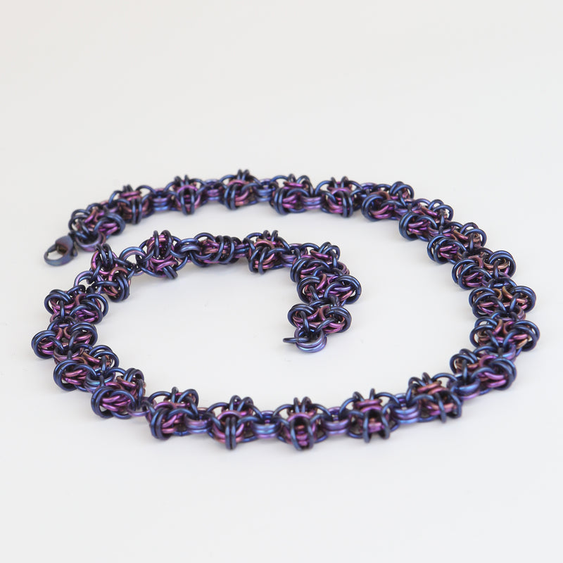 Intricately linked icy blue and rich purple chain necklace displayed in a neat spiral