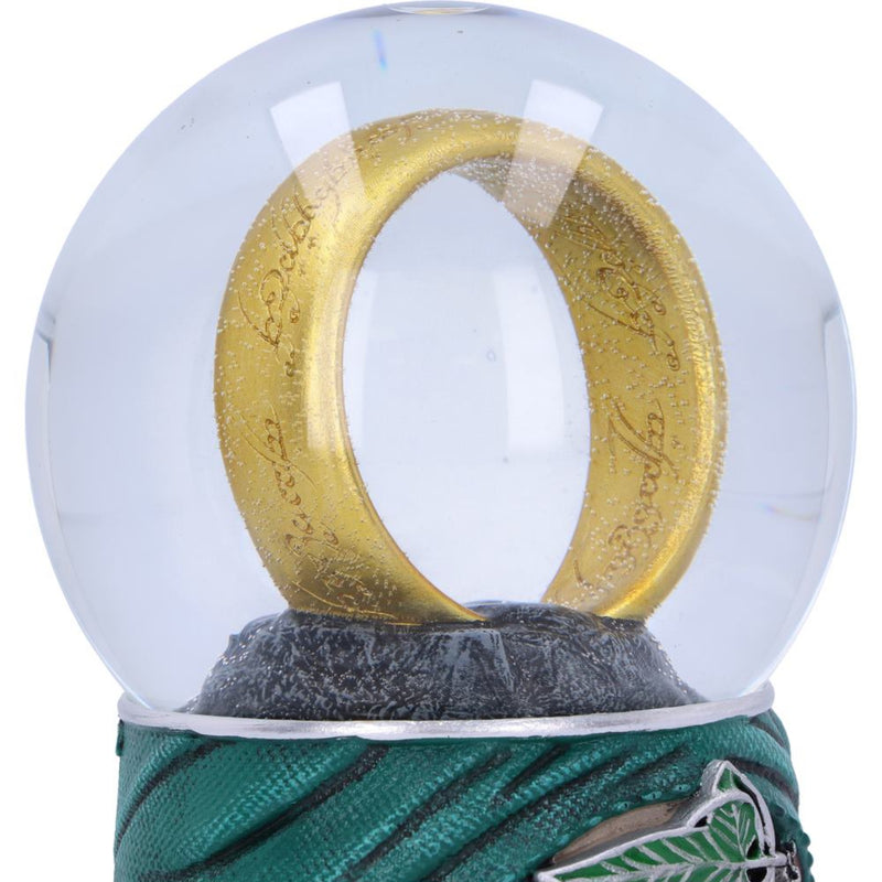 Gold ring with engraved text inside a transparent snow globe on a green and black striped base.
