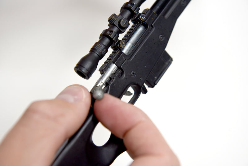 Close up of the model L96A1. The model is being held and the hammer is being pulled back with a thumb and index finger