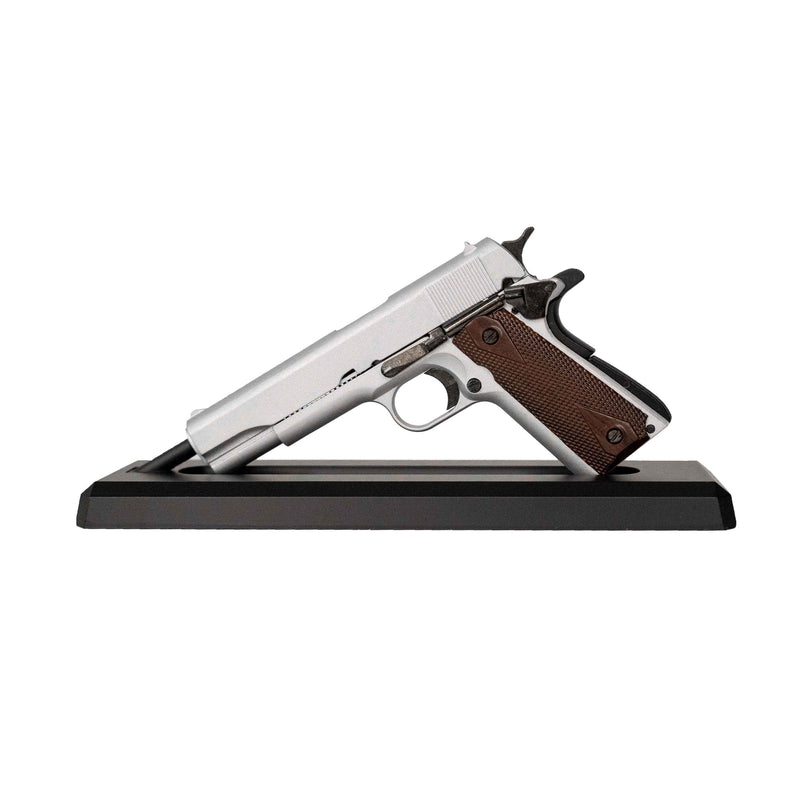 Silver model 1911 mounted on its display stand pointing to the left