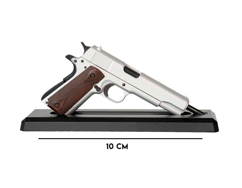 Silver 1911 model on its display mount facing towards the right. There is a label underneath indicating that the gun is 10cm long
