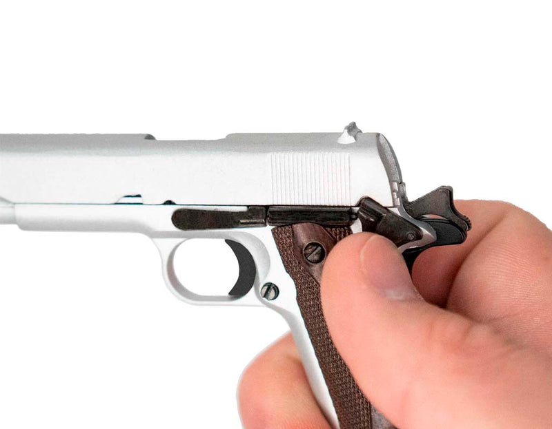 Close up of the 1911 model. The model is being held in one hand, the thumb on the thumb safety.