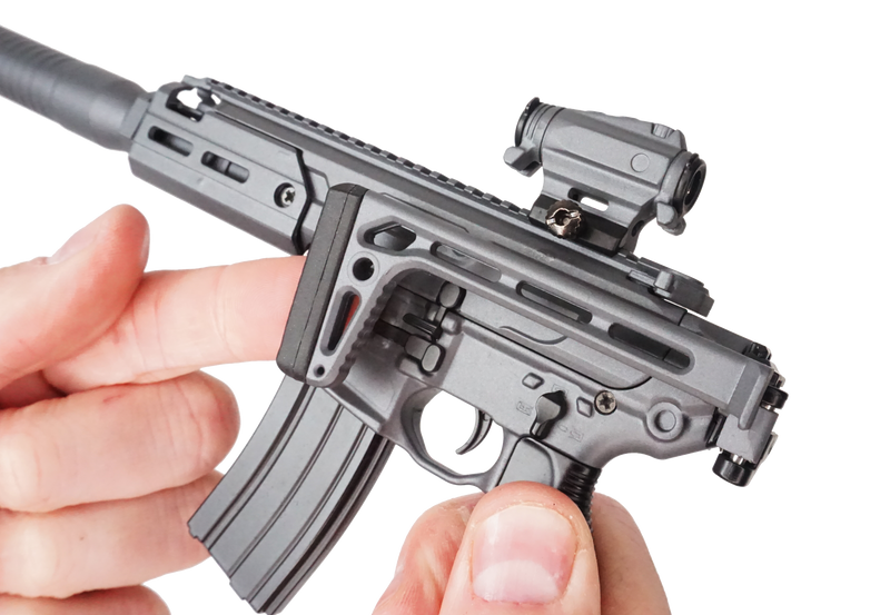 Close up of the SIG MCX model being held in two hands. The right hand is supporting the model and the left is adjusting the folding stock.