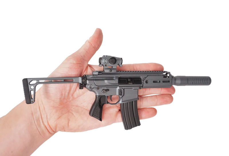 Stone grey SIG MCX model resting on the palm of a hand, indicating its small scale.