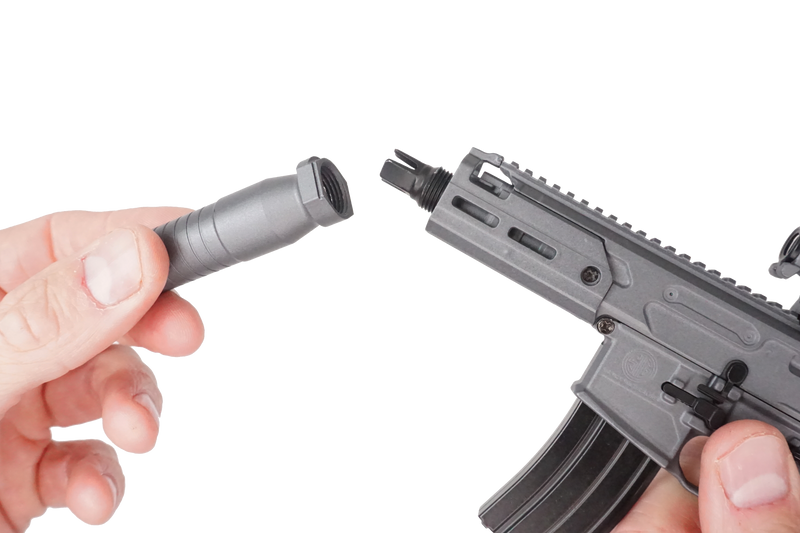 Close up of the SIG MCX model being held in two hands. The right hand is supporting the model and the left is adjusting the suppressor 