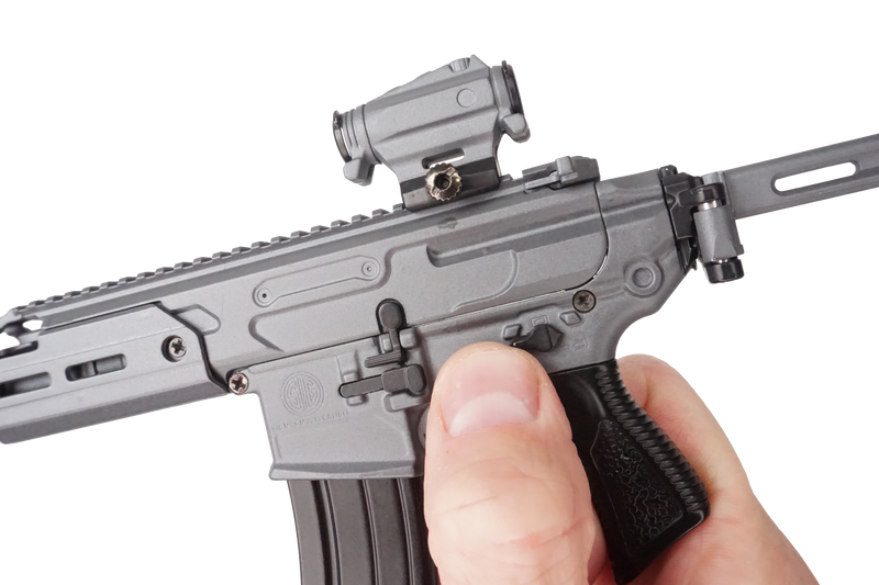 Close up of the SIG MCX model being held in a hand, with a thumb on the fire selector.
