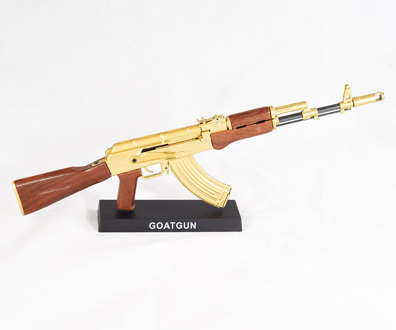 Completed model of gold plated AK47 gun on a black display stand that reads 'GOATGUN'.