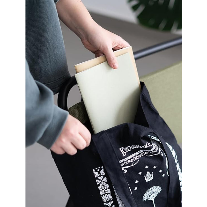 person putting notebooks inside black tote bag