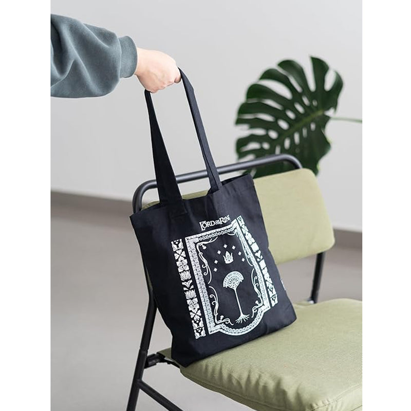 hand picking up a black tote bag from a chair