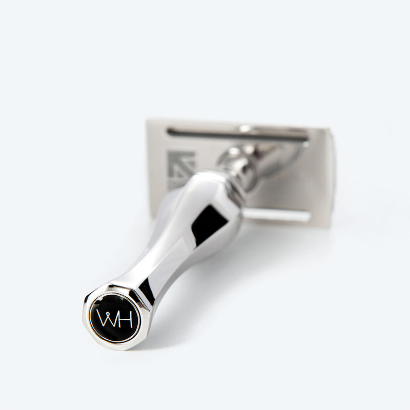 Line of Kings' Eltham Stainless Steel Safety Razor Lying on its side full view with focus on the razors handle and the WH initials stamped on the end