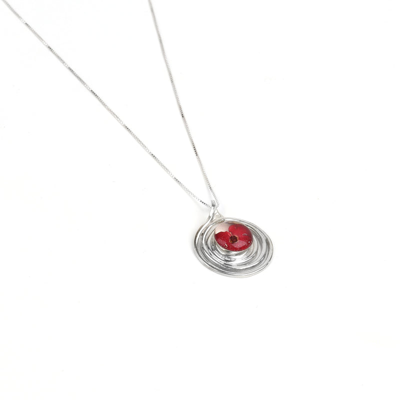 Spiral poppy pendant necklace lying flat