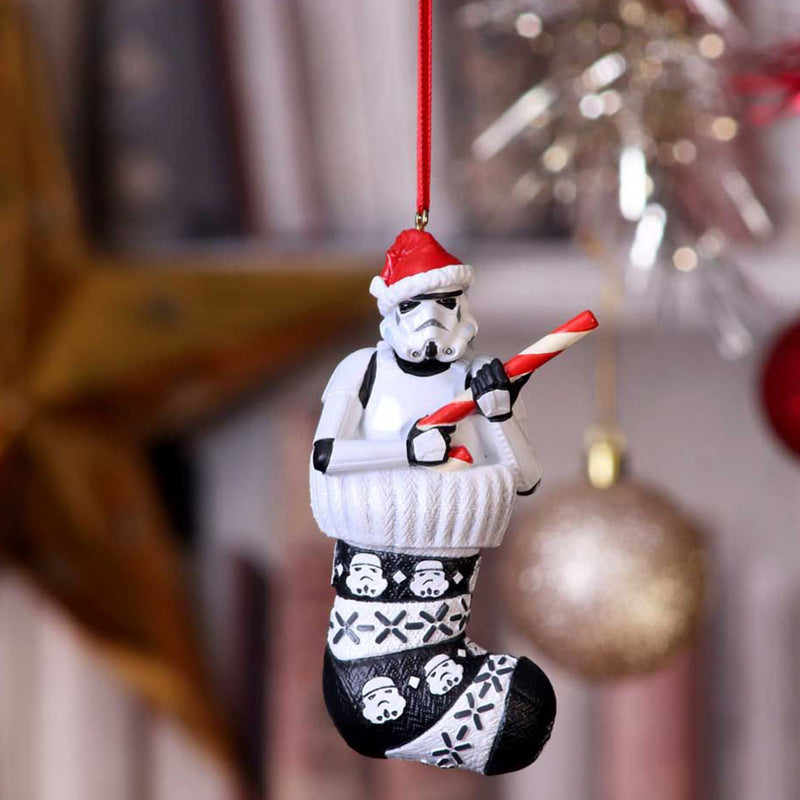 Stormtrooper in a stocking holding a candy cane like a blaster hanging decoration in festively decorated room