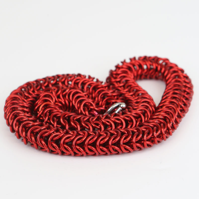 Intricately linked chunky chainmail necklace in crimson red displayed in a neatly coiled pile