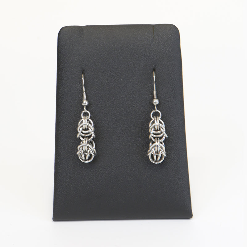 silver coloured byzantine knot drop earrings on a black display stand