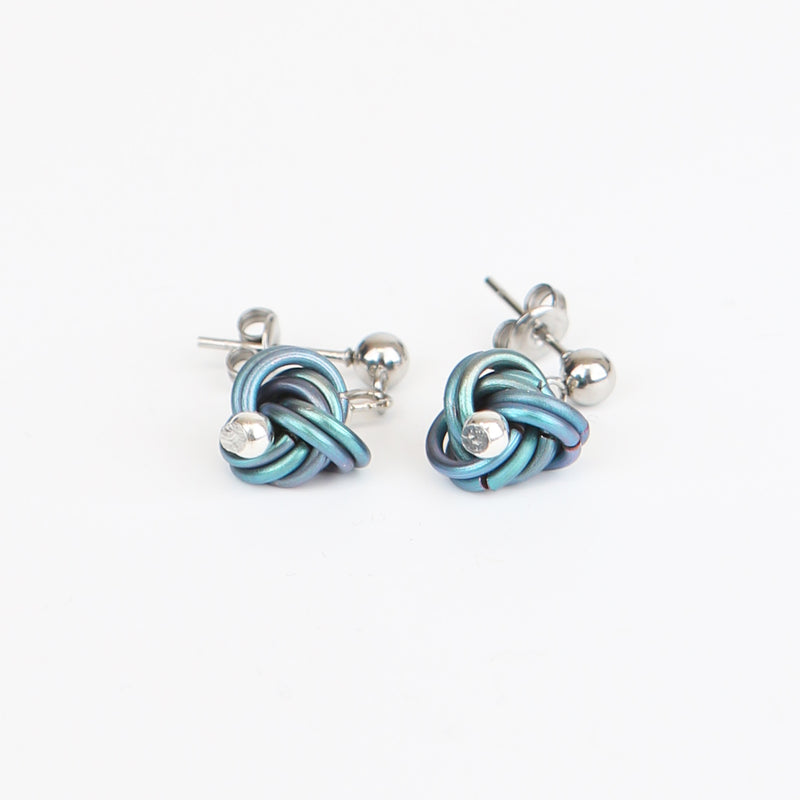 Close up of silver stud earrings with looping blue chain details