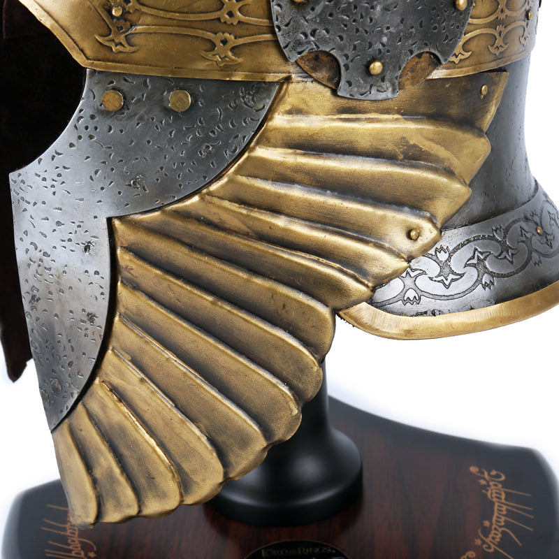 Close-up of a detailed helmet with gold and silver coloured plating on a stand.