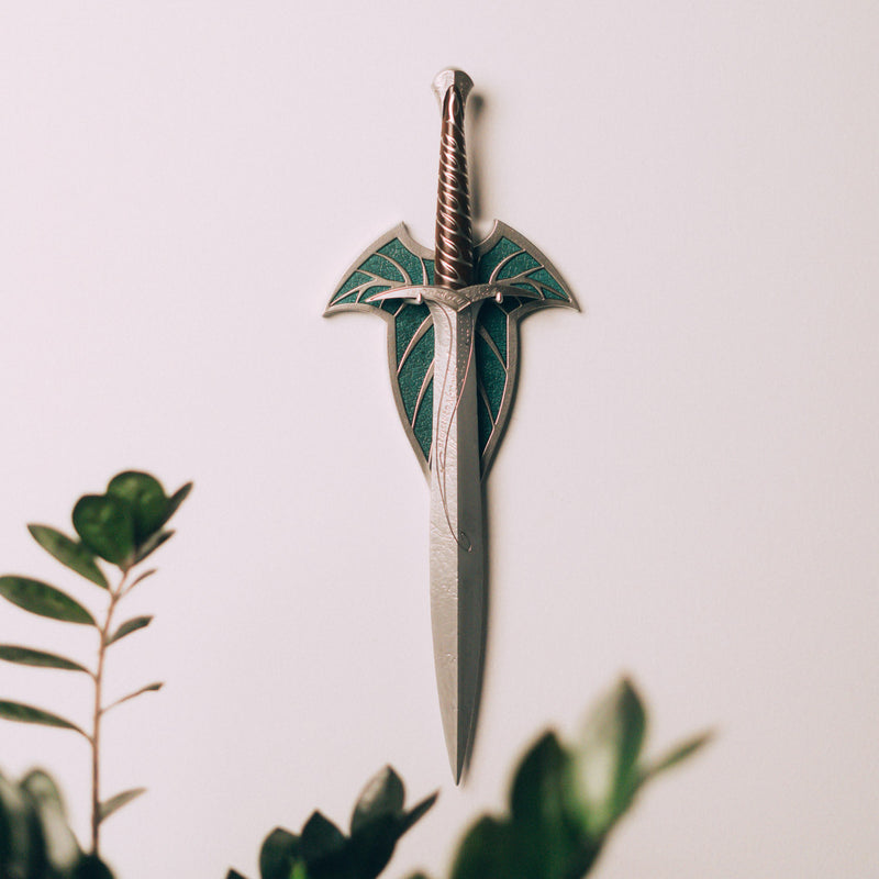 Decorative sword with green blade and silver hilt on a light background