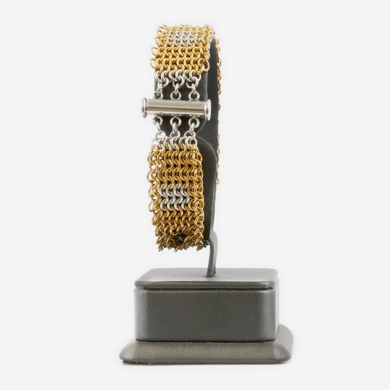 Gold and silver chain bracelet showing the clasp on a black stand against a white background 