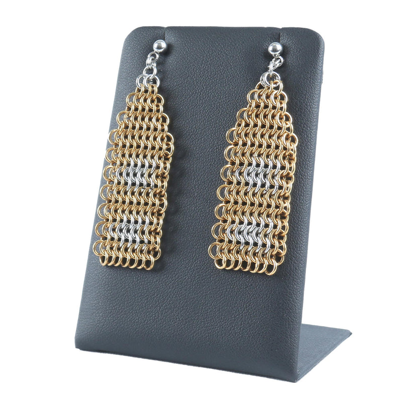 Pair of gold and silver chainmaille earrings on a black stand.