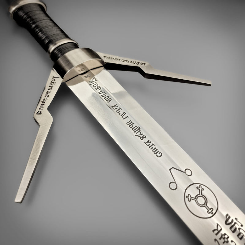 Triple-pronged metallic weapon with engraved text on a gray background