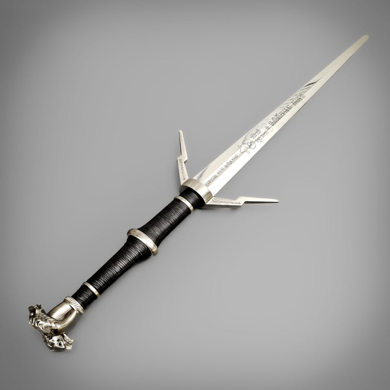 Decorative dagger with a black and silver handle on a gray background