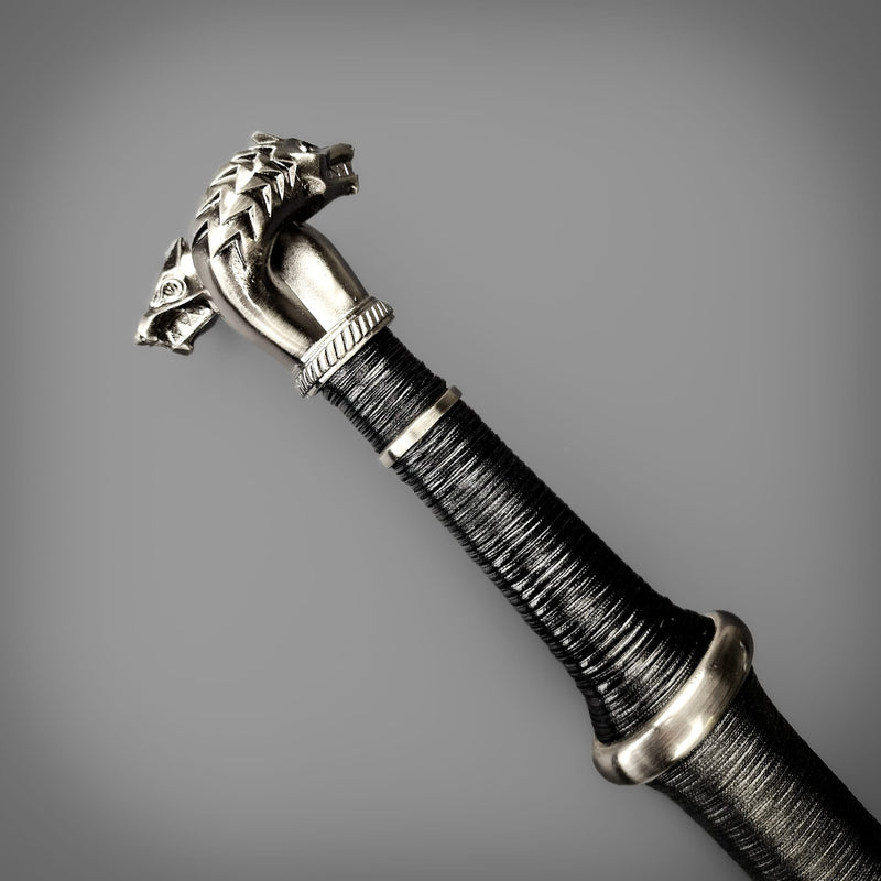 Decorative sword handle with intricate design on a gray background