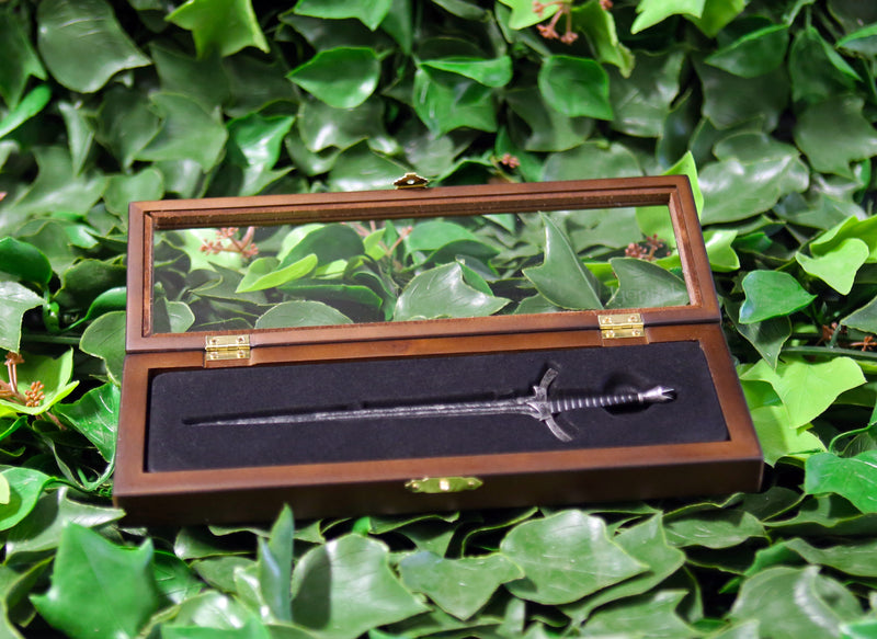 Morgul blade replica letter opener in open wooden display case on a bed of ivy